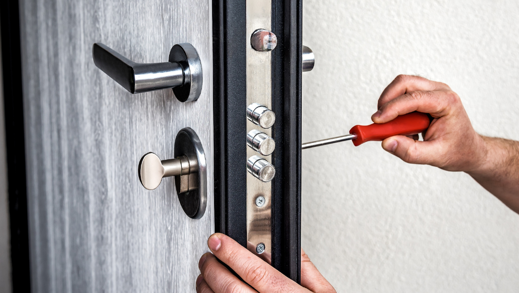 Man fixing a security door with a screwdriver