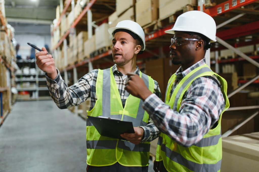 Two warehouse workers are walking through the facility, engaged in conversation about logistics
