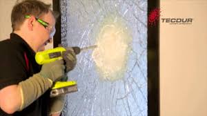 Man with a drill breaking some security glass
